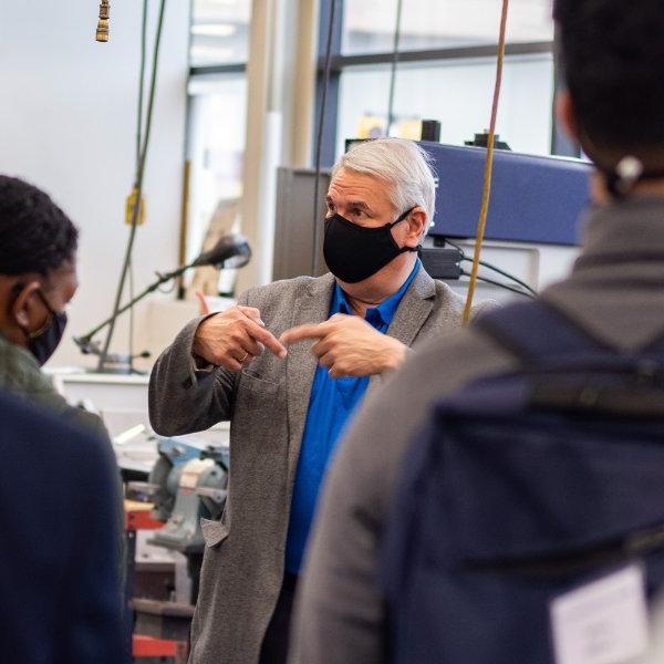 Paul Plotkowski, masked in center, talks with students in the engineering building.